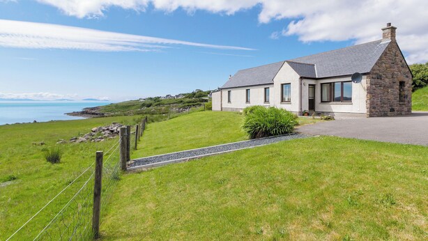 A stone house with a sloped roof, a satellite dish, and a view of the sea. - 3 bedroom accommodation in Gairloch (Gairloch)