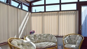 A sunlit room with a large window, two wicker chairs, a sofa, and a small table with a vase of flowers. - 1 bedroom accommodation in Bunbury (Bunbury)