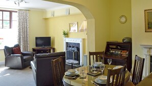 A living room with a fireplace, a television, a sofa, and a dining area set for a meal. - 1 bedroom accommodation in Bunbury (Bunbury)