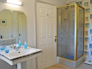 A bathroom with a white sink, a mirror, a shower with a glass door, and a wall with nautical-themed wallpaper. - 1 bedroom accommodation in Bunbury (Bunbury)