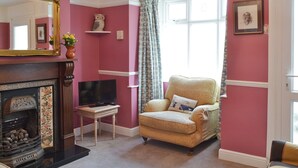 A living room with a fireplace, a television, and a comfortable armchair.