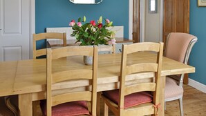 A dining area with a wooden table and chairs, a vase of flowers, and a mirror on the wall.