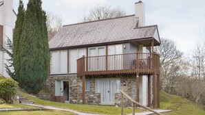 A two-story stone house with a balcony, a stone staircase leading to the entrance, and a large coniferous tree in the yard. - 3 bedroom accommodation in St Mellion, near Saltash (St Mellion, near Saltash)