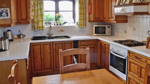 A kitchen with wooden cabinets, a microwave, a sink, and a stove. - 2 bedroom accommodation in Trelawnyd, near Prestatyn (Trelawnyd, near Prestatyn)