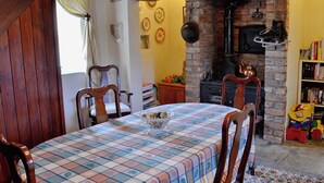 A dining area with a checkered tablecloth, wooden chairs, a brick fireplace, and a bookshelf with books. - 2 bedroom accommodation in Trelawnyd, near Prestatyn (Trelawnyd, near Prestatyn)