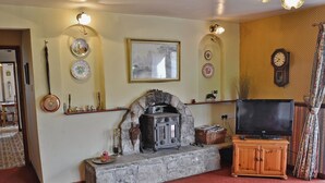 A living room with a stone fireplace, television, and decorative plates on the wall. - 2 bedroom accommodation in Trelawnyd, near Prestatyn (Trelawnyd, near Prestatyn)