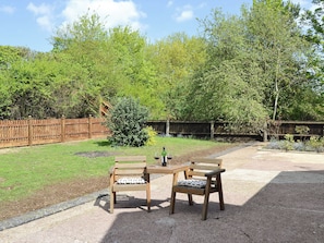 An outdoor seating area with two wooden tables and chairs, a small bush, and a wooden fence. - 1 bedroom accommodation in Cawston, near Norwich (Cawston, near Norwich)