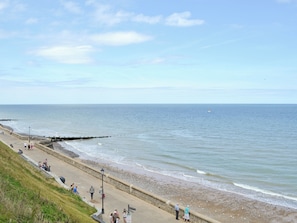 A coastal walkway with a stone wall, a sandy beach, and a calm sea. - 1 bedroom accommodation in Cawston, near Norwich (Cawston, near Norwich)