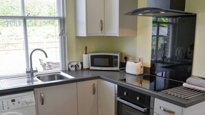 Een kleine keuken met een wasmachine, magnetron, broodrooster en oven.