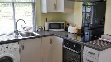 A compact kitchen with a washing machine, microwave, toaster, and oven.
