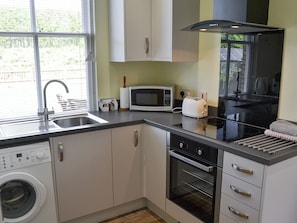 A compact kitchen with a washing machine, microwave, toaster, and oven. - 1 bedroom accommodation in Cawston, near Norwich (Cawston, near Norwich)
