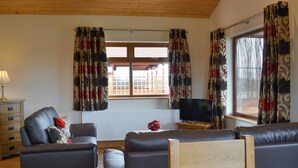 A living room with a sofa set, a television, and a window with curtains. - 2 bedroom accommodation in Burgh le Marsh, near Skegness (Burgh le Marsh, near Skegness)