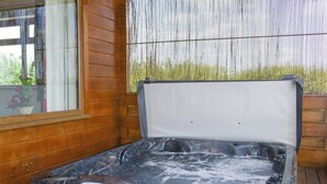 A hot tub with a wooden deck and a window with a view of greenery. - 2 bedroom accommodation in Burgh le Marsh, near Skegness (Burgh le Marsh, near Skegness)