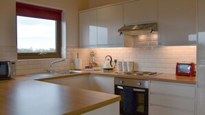 A modern kitchen with a large island, stainless steel appliances, and white cabinetry. - 2 bedroom accommodation in Burgh le Marsh, near Skegness (Burgh le Marsh, near Skegness)