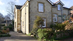 Une maison en pierre avec une allée pavée et un petit jardin.