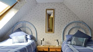 A bedroom with two beds, a nightstand, a mirror, and a window.