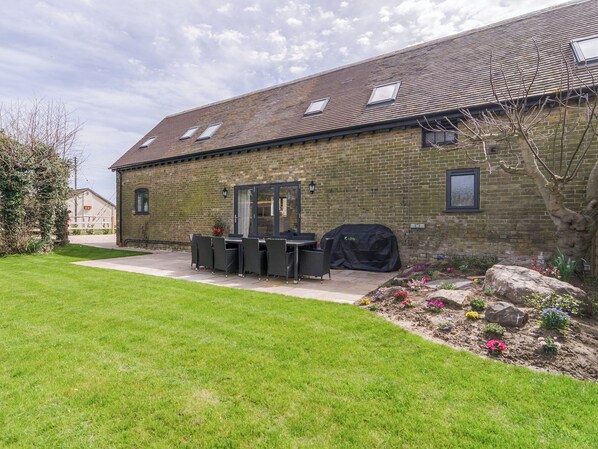 A brick building with a patio area, outdoor seating, and a barbecue grill.