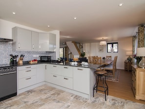 A modern kitchen with white cabinets, a black microwave, and a dining area with a wooden table and chairs.