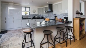A modern kitchen with a marble countertop, stainless steel appliances, and a clock on the wall. - The Coach House - UKC2772 (Sandwich Bay, near Sandwich)