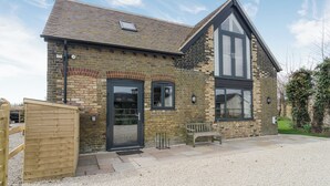 A two-story brick house with a dark front door, two windows, a sloped roof, and a wooden bench outside. - The Coach House - UKC2772 (Sandwich Bay, near Sandwich)