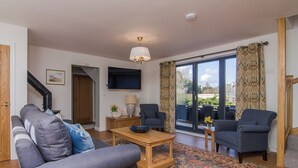 A living room with a sofa, chairs, a coffee table, a TV, and a view through the glass door. - The Coach House - UKC2772 (Sandwich Bay, near Sandwich)