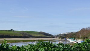 Eine Küstenlandschaft mit Booten, viel Grün und Hügeln im Hintergrund.