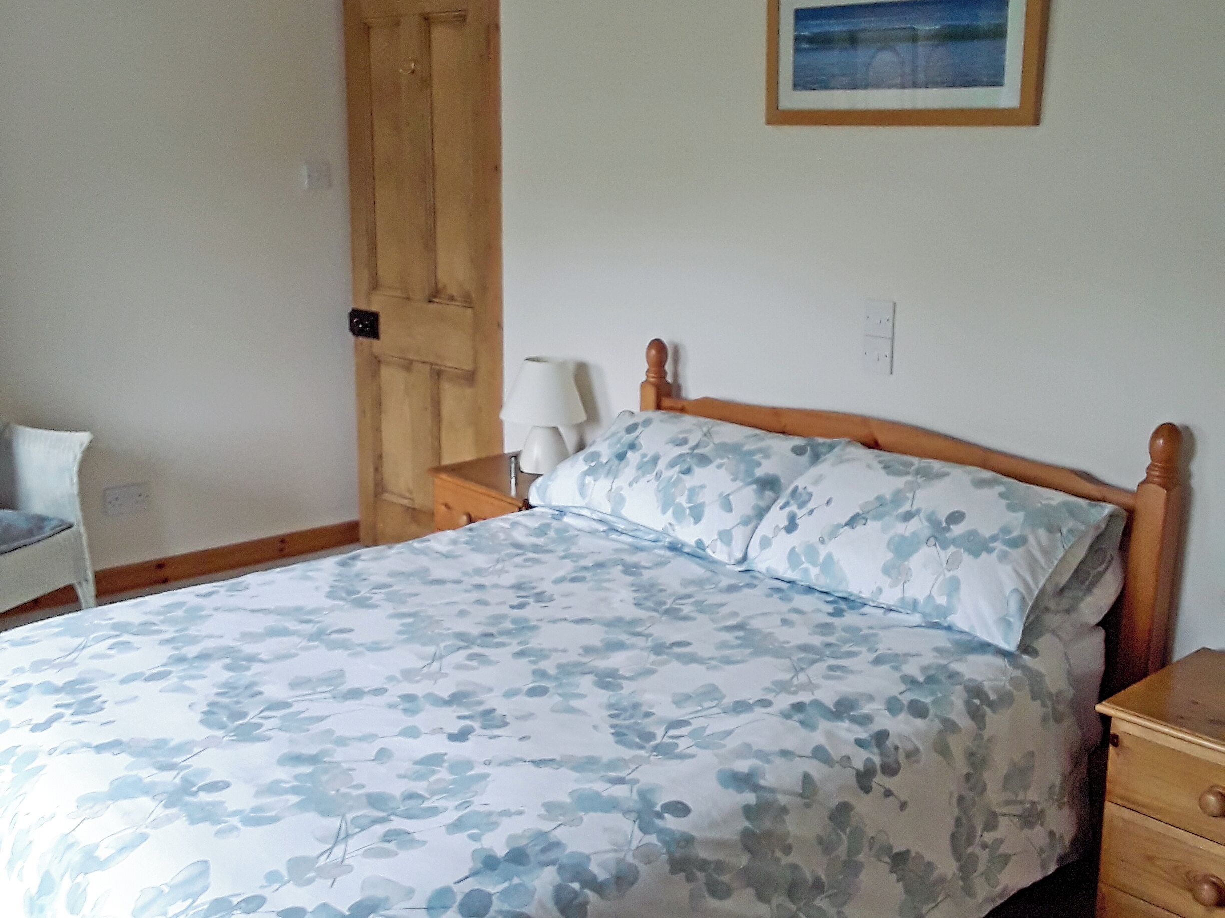 Une chambre à coucher avec un lit en bois, une table de chevet avec une lampe et une porte.