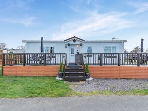 A two-story house with a wooden deck, a front porch, and a mailbox.