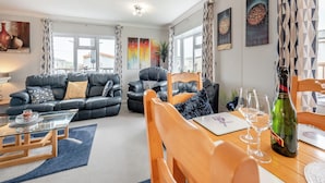 A modern living room with a glass coffee table, leather sofas, and a wooden dining table with chairs. - 2 bedroom accommodation in Dinas, near Fishguard (Dinas, near Fishguard)