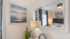 A bedroom with a bed, a bedside table with a lamp, a mirror, and a painting on the wall. - 2 bedroom accommodation in Dinas, near Fishguard (Dinas, near Fishguard)