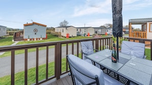 A deck with outdoor seating and a view of mobile homes. - 2 bedroom accommodation in Dinas, near Fishguard (Dinas, near Fishguard)