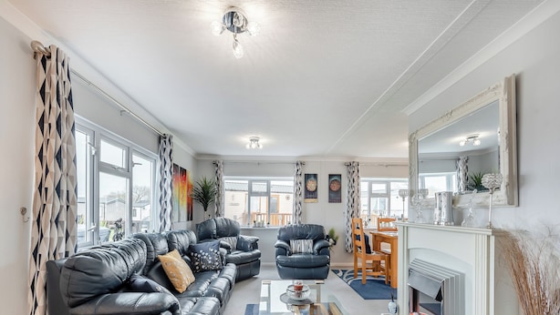 A modern living room with a black leather sofa, a glass coffee table, and a fireplace. - 2 bedroom accommodation in Dinas, near Fishguard (Dinas, near Fishguard)