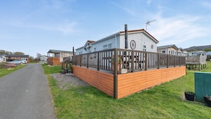 A caravan park with wooden fences, a paved path, and a grassy area. - 2 bedroom accommodation in Dinas, near Fishguard (Dinas, near Fishguard)
