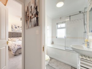 A bedroom with a bed, a bathroom with a bathtub, and a shower.