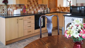 Een moderne keuken met houten kastjes, een zwart aanrecht en een vaatwasser.