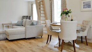 Un salon moderne avec un canapé, une table à manger et des chaises. Une échelle en bois est appuyée contre le mur.