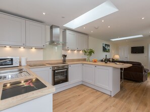 A modern kitchen with white cabinets, a built-in oven, and a large island with a sink. - Sherwood Forest Lodge 1 (Kings Clipstone, near Mansfield)