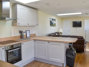 A modern kitchen with white cabinetry, a built-in oven, and a wooden countertop.