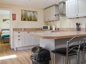 A modern kitchen with a wooden countertop, white cabinets, a stainless steel range hood, a microwave, and a coffee maker. - Sherwood Forest Lodge 1 (Kings Clipstone, near Mansfield)