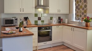 Una cocina moderna con armarios blancos, una campana extractora de acero inoxidable, un microondas y un horno empotrado.