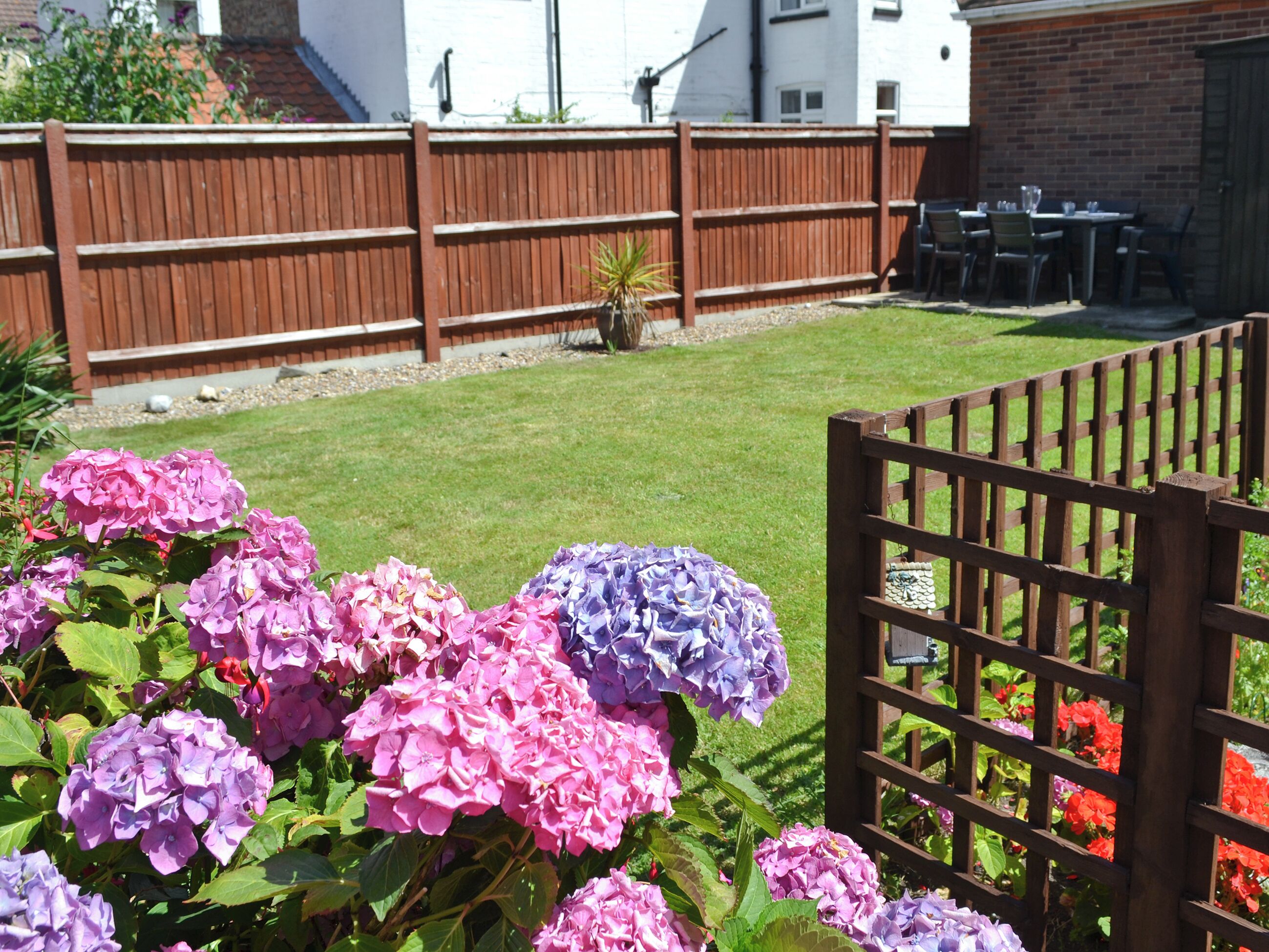 A backyard with a wooden fence, a lawn, and a table with chairs.