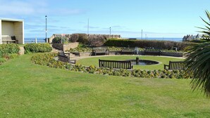 Un jardin bien entretenu, agrémenté de bancs, d’une fontaine et offrant une vue sur la mer.