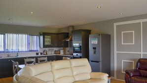 A modern kitchen with dark cabinets, a built-in oven, and a refrigerator. - Aimmee's Lodge - UKC2203 (Doddington, near Lincoln)
