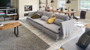 A modern living room with a grey sofa, a wooden coffee table, and a dining area with a wooden table and chairs. - 4 bedroom accommodation in Beck Hole, near Whitby (Beck Hole, near Whitby)