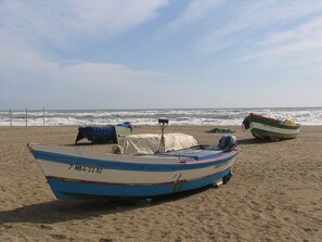 Una playa con dos barcos, uno en primer plano y otro al fondo.