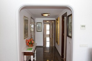 A hallway with a bench, framed pictures, and a door at the end.