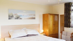 Ein Schlafzimmer mit Bett, Nachttisch, Lampe, Holzschrank und einem Bild an der Wand.