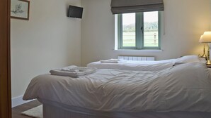 A bedroom with two beds, a window with a view, a flat-screen TV, and a lamp.