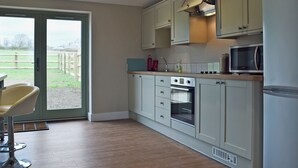 A modern kitchen with a large window, wooden flooring, and built-in appliances.