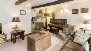 A cozy living room with a piano, wooden furniture, and wall-mounted lights. - 3 bedroom accommodation in Barley, near Barrowford (Barley, near Barrowford)